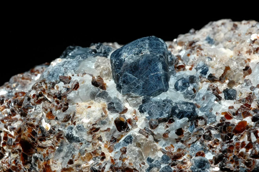 8 Metamorphic Minerals and Metamorphic Rocks Sapphirine (blue) is a rare high-temperature aluminous mineral. Red garnet and quartz are also seen in this photo.
