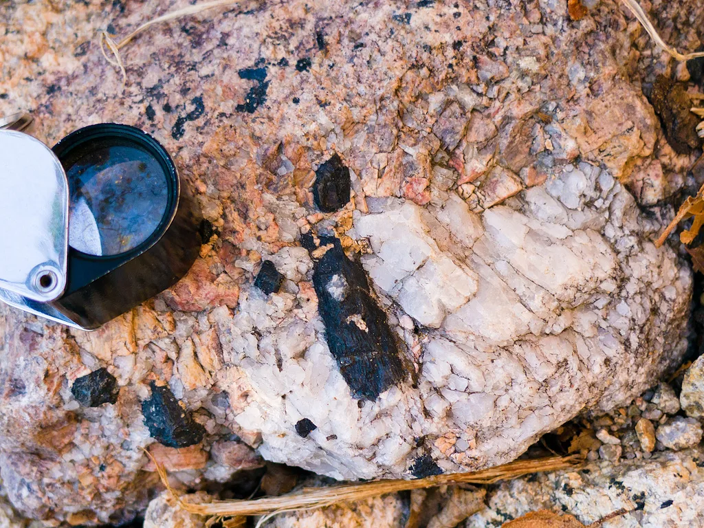 4 Crystals and Crystallization A typical pegmatite containing quartz, and alkali feldspar and tourmaline (black)