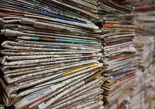 A photograph of a several stacks of newspapers, viewed from the side.