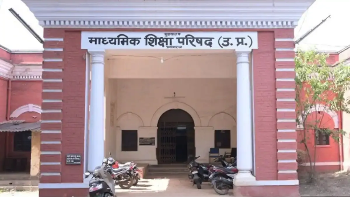A student marking important dates on the UP Board Academic Calendar 2026-27 with a red pen.