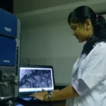 A medical student in a white coat studying in a modern university library, representing the increase in Jharkhand medical seats.