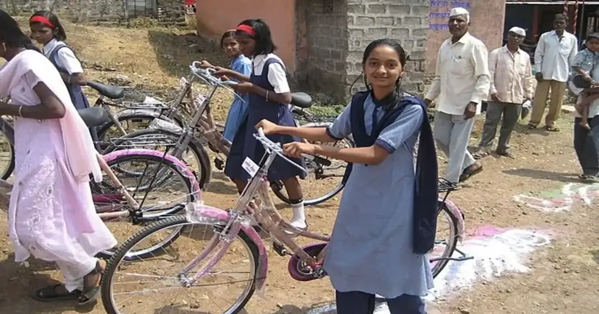 A smiling girl student in her school uniform proudly stands with her new bicycle provided by the Delhi government initiative.