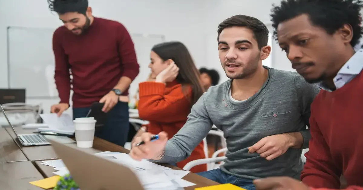 A diverse group of young students collaborating on laptops in a modern classroom, learning about artificial intelligence.