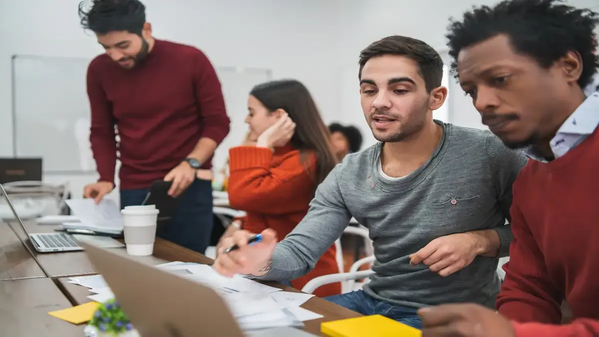A diverse group of young students collaborating on laptops in a modern classroom, learning about artificial intelligence.