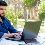 A student looking at their GATE 2026 Result on a laptop screen, feeling happy and successful.