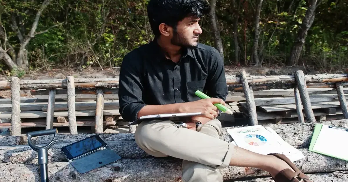 A group of diverse college students working together on a biodiversity project in a lush green forest setting.
