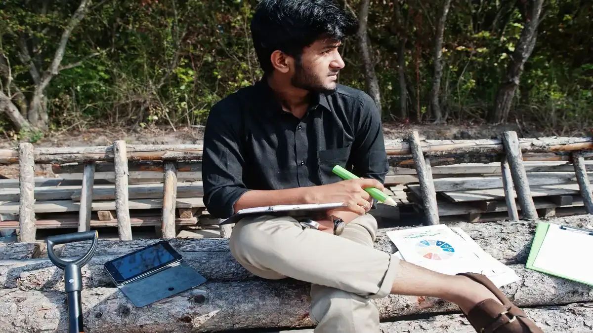 A group of diverse college students working together on a biodiversity project in a lush green forest setting.