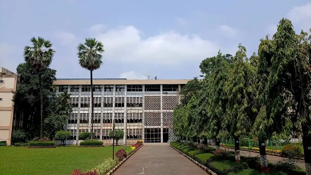 A student looking thoughtfully at the IIT Bombay campus building, representing the IIT JAM 2026 counselling process for MSc admissions.