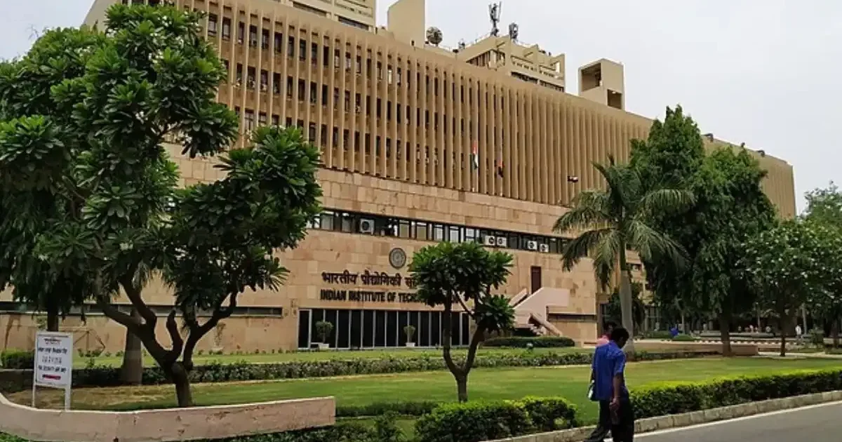An aerial view of the Indian Institute of Technology (IIT) Delhi campus, showcasing its academic buildings and lush green lawns under a clear sky.