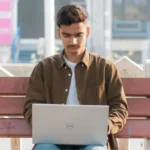 A student anxiously checking their laptop for the JEE Main 2024 Session 2 city intimation slip on the StudyHub news portal.