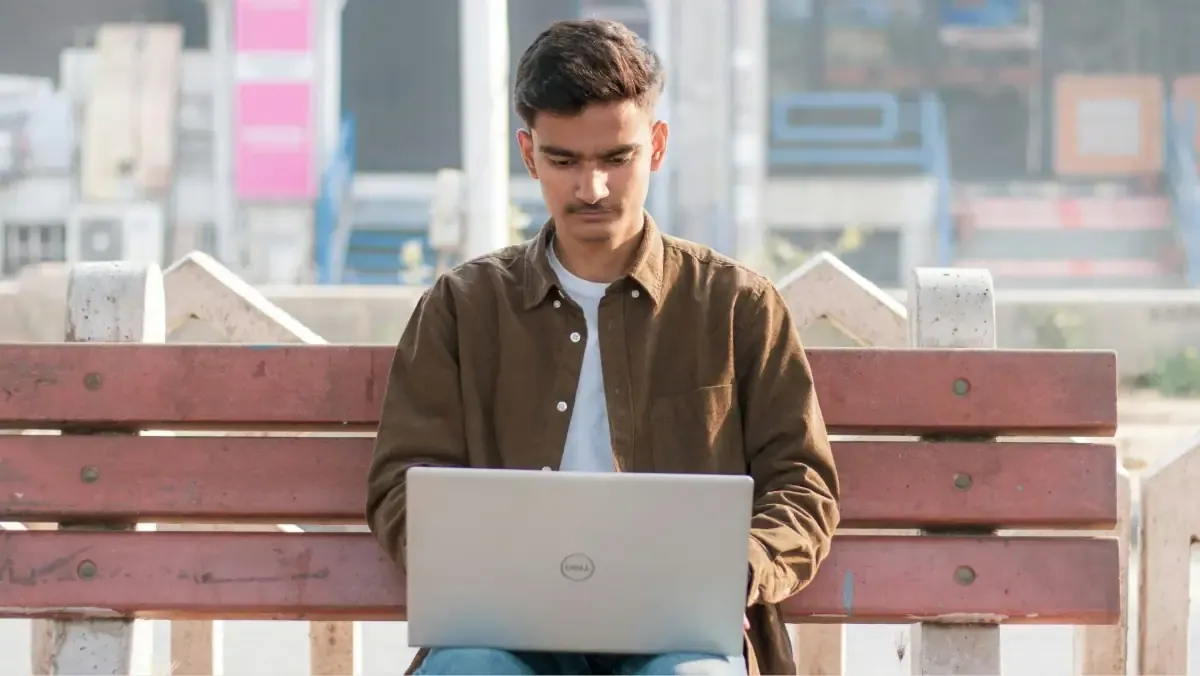 A student anxiously checking their laptop for the JEE Main 2024 Session 2 city intimation slip on the StudyHub news portal.