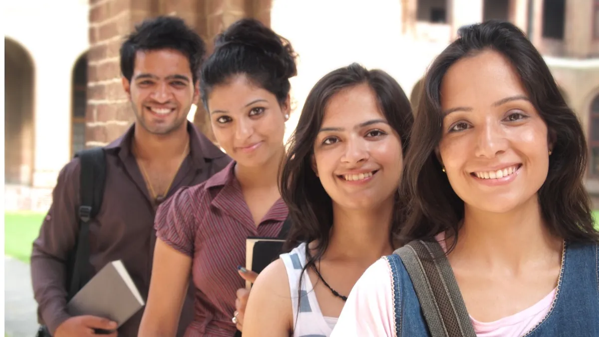 A student sitting at a desk in an examination hall, focused on their MAH MCA CET 2026 paper with an admit card visible.