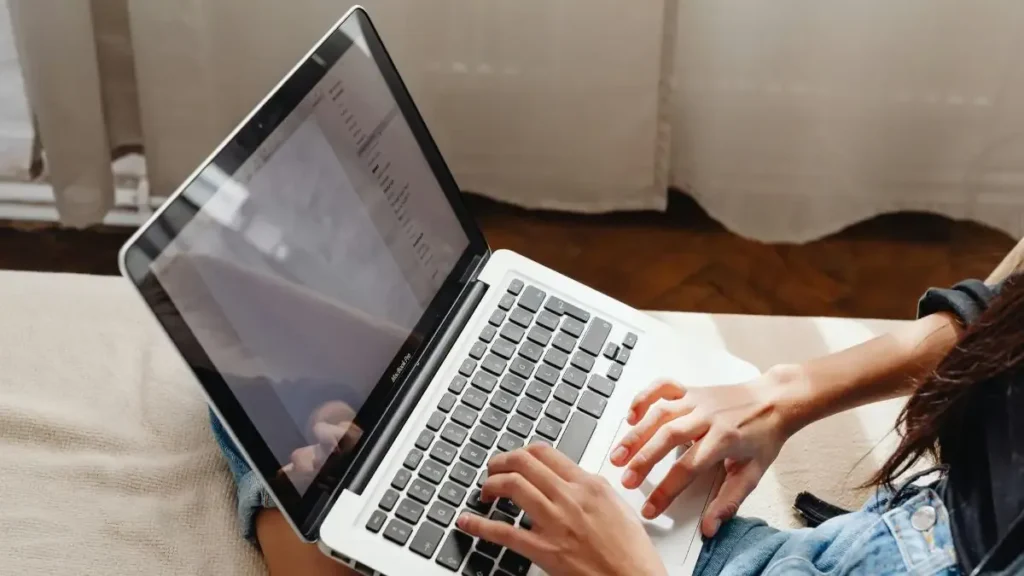 A student checking their NIFTEE 2026 Result on a laptop screen, looking relieved and happy.