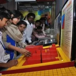 A student marking answers on an OMR sheet for the UP TET 2026 exam, with a calendar showing the application dates in the background.